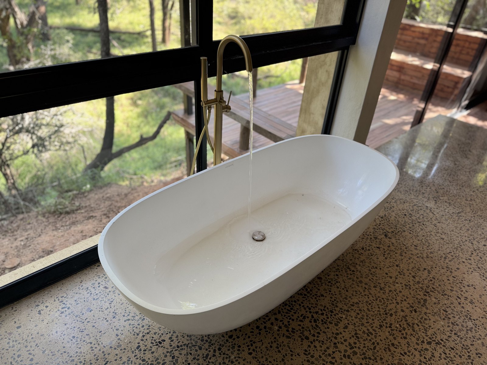 Freestanding stone bath with brass mixer overlooking the bush — Madikwe lodge